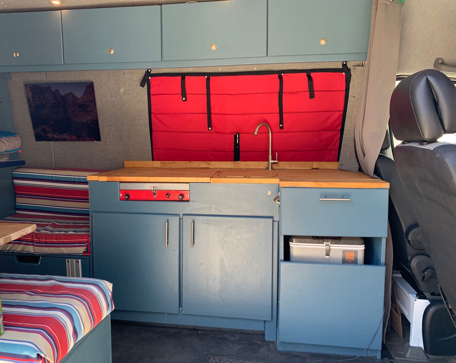 and a full kitchenette with wooden counters.|White Sprinter van (ideal for RV rental) parked on a sunny residential street with houses and a stop sign.|Inside an RV rental: a compact kitchen with a two-burner stove