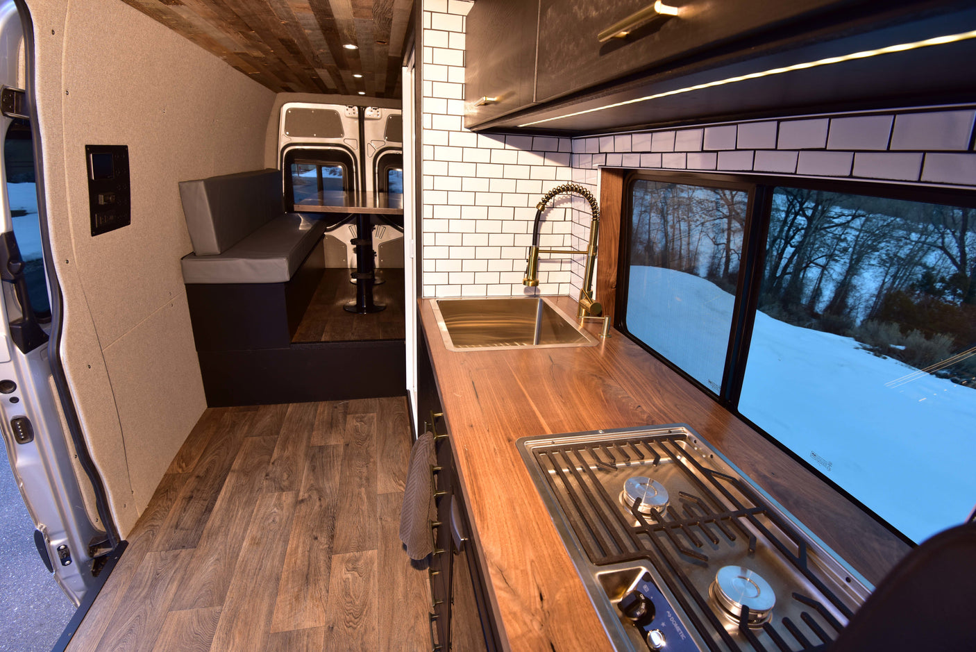 Step inside this inviting rv rental. Cozy camper van interior with wood floors, modern kitchen, and dining area.