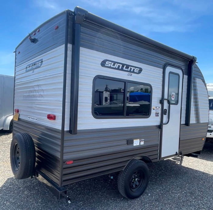seen from the side on gravel. Features an awning. Ideal for rv rental adventures.|Compact Sun Lite LTD travel trailer