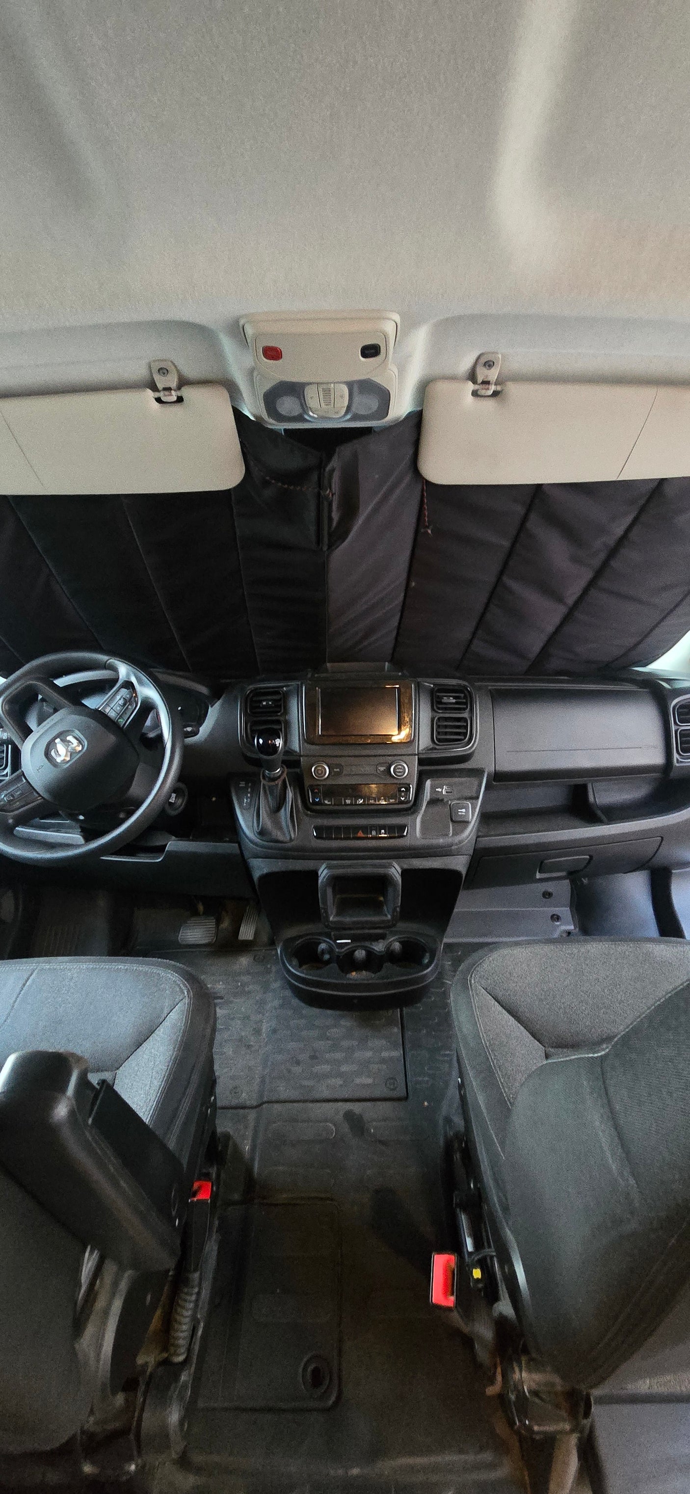 RV rental interior: view of dashboard, steering wheel, and front seats with sunshade installed.