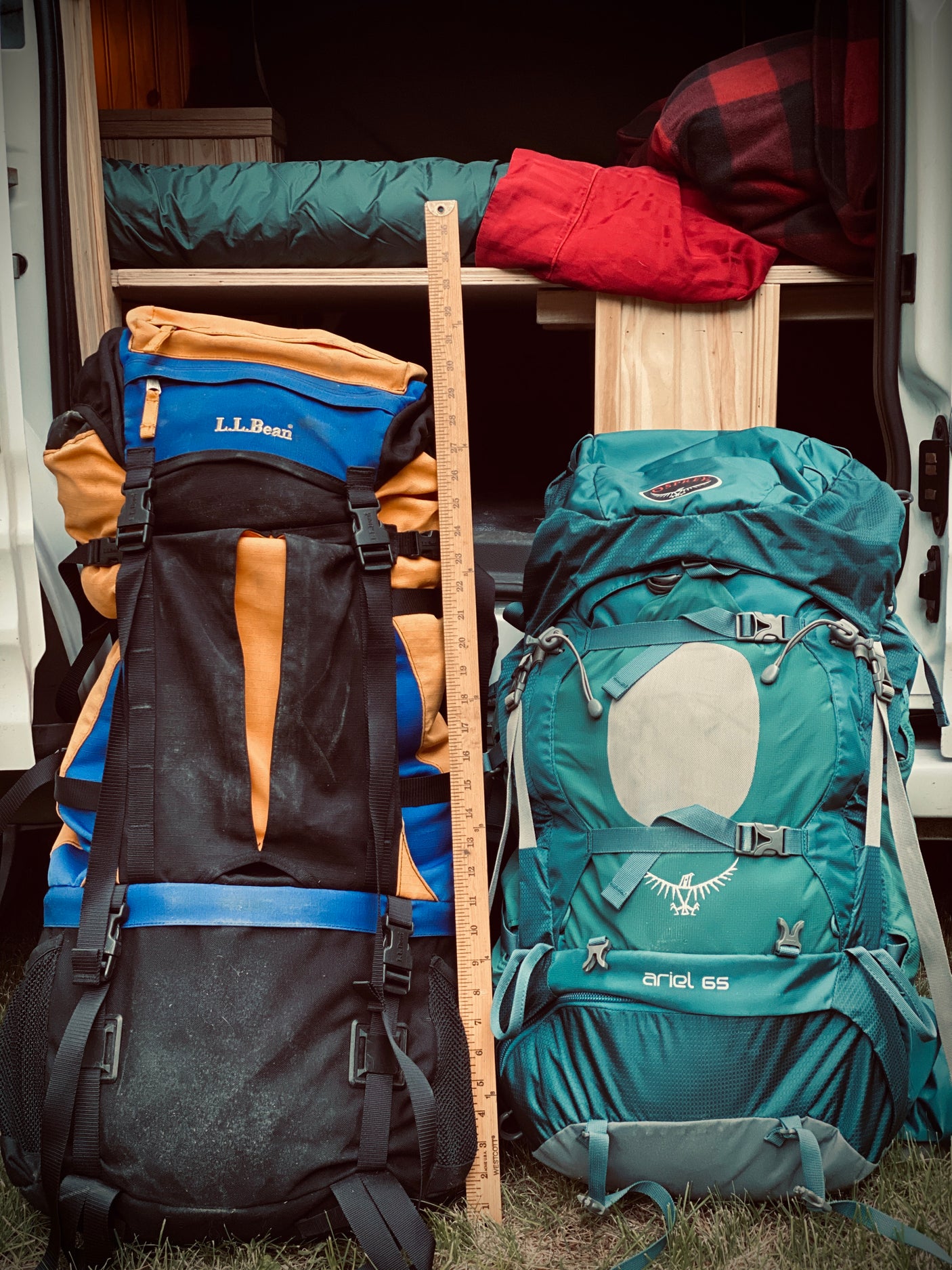 Two large backpacks, L.L.Bean & Osprey Ariel 65, measured by a ruler inside an RV rental. Ready for adventure.