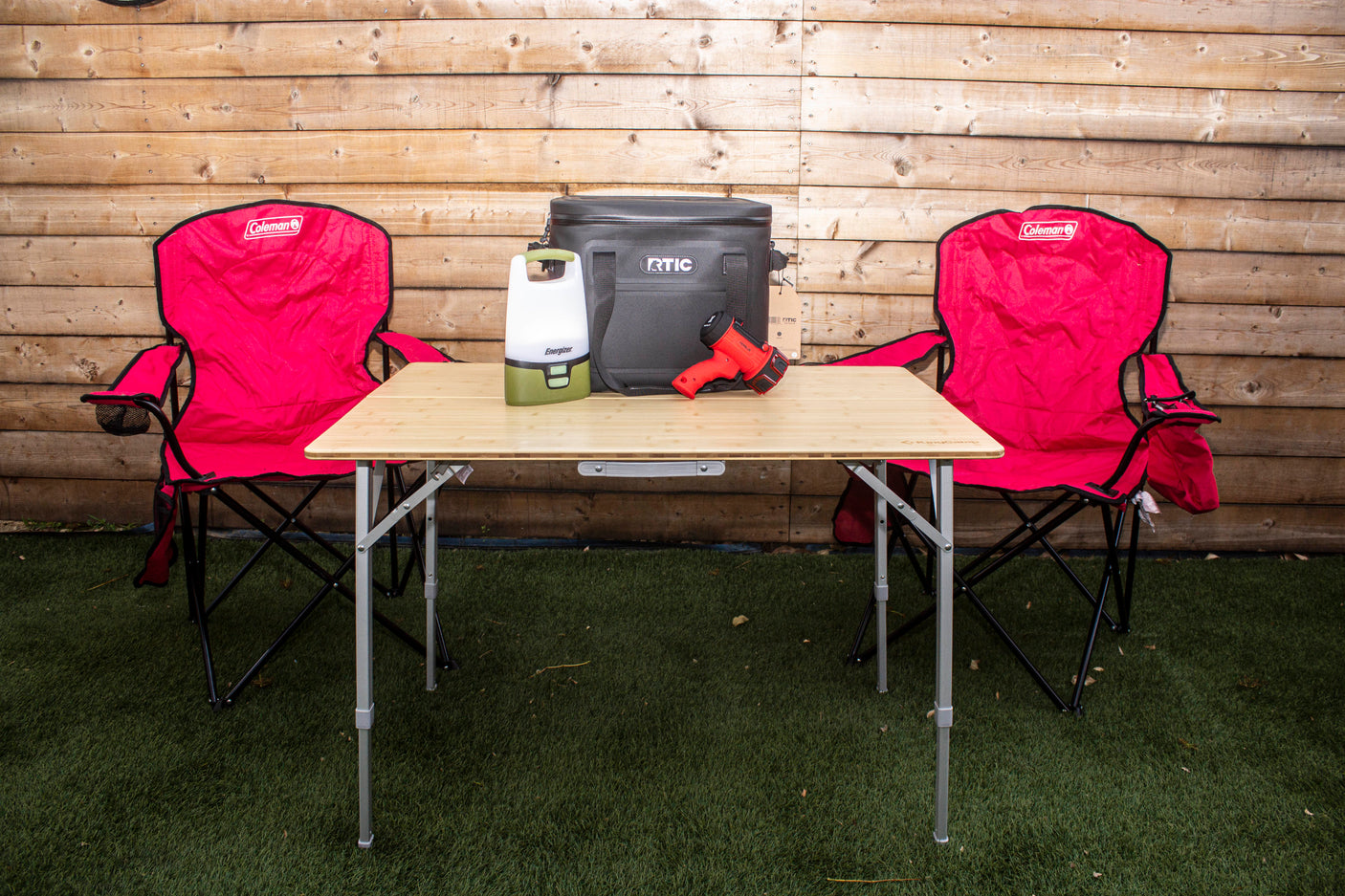 RV rental camping essentials: Coleman chairs, foldable table, RTIC cooler, lantern, & spotlight for outdoor adventures.
