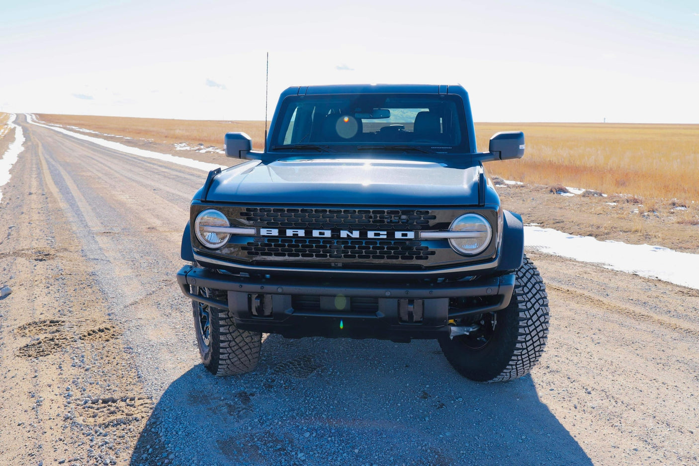 A black Ford Bronco SUV on a snowy gravel road, ready for adventure. A rugged alternative to an RV rental.