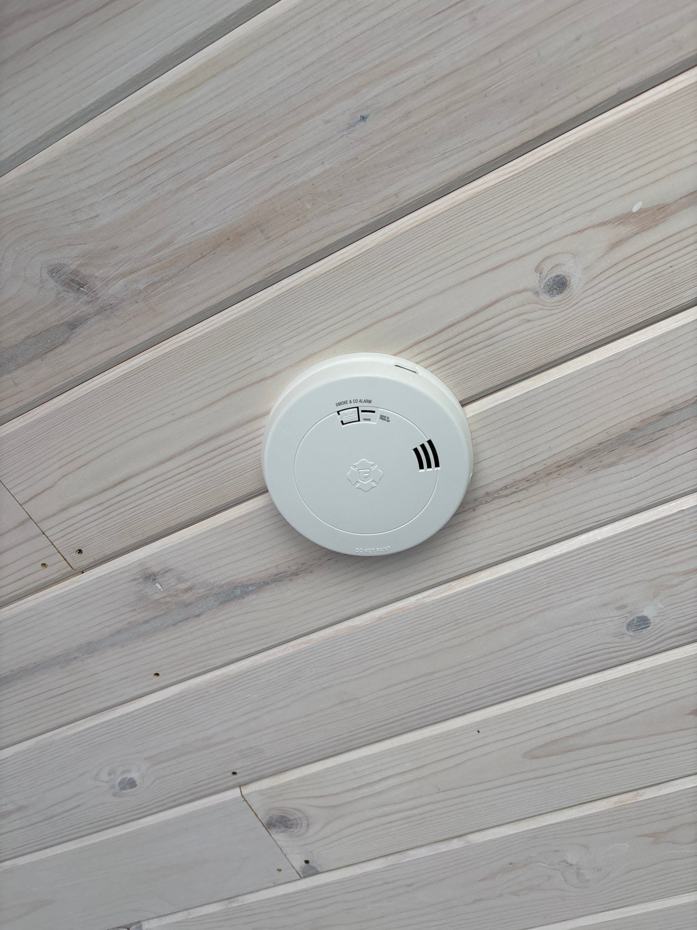 Safety first for your RV rental: A smoke and CO alarm on a light wood ceiling.