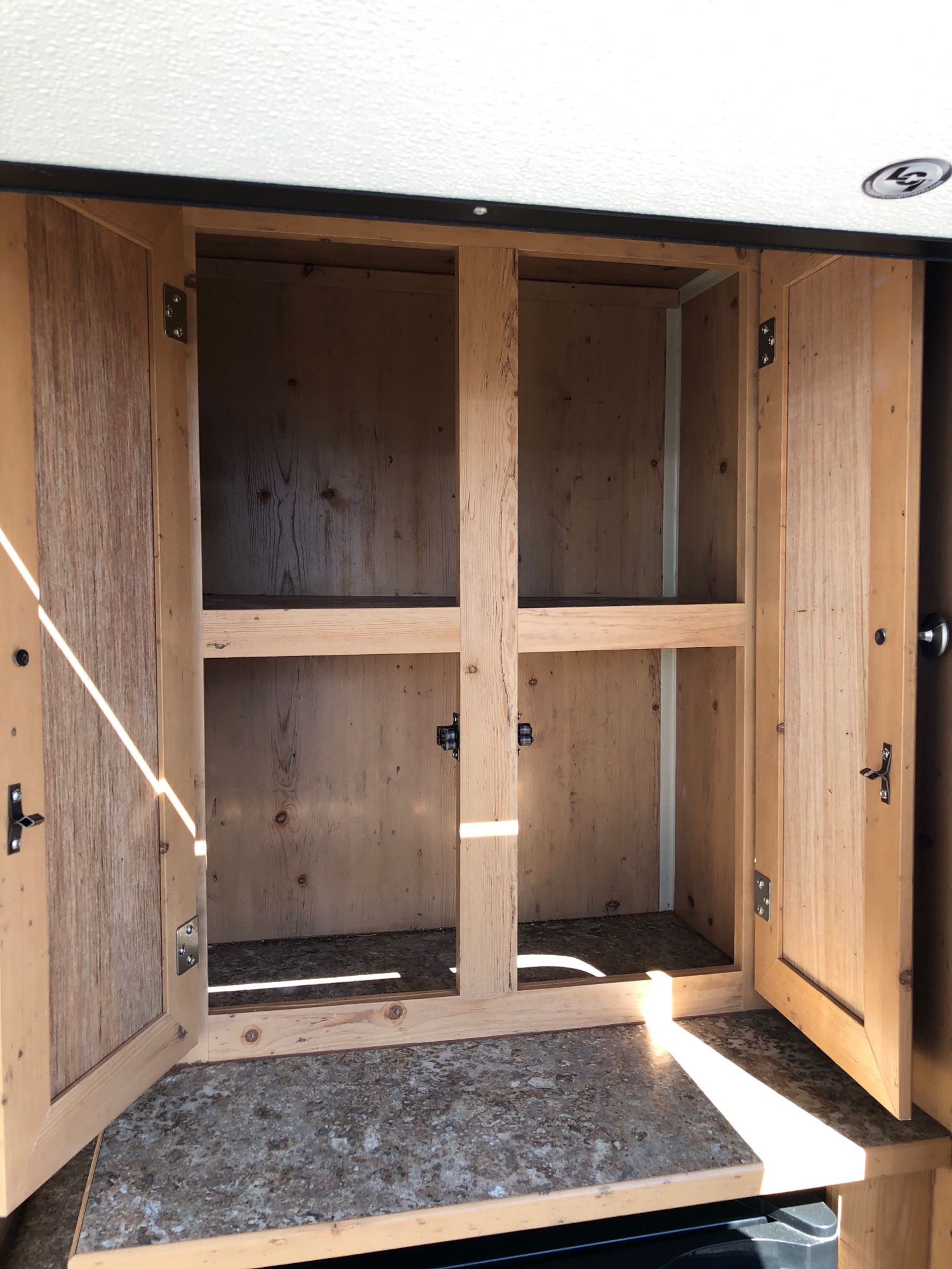 parked on gravel with other RVs in the background.|Step inside this RV rental! Features a black upholstered bench