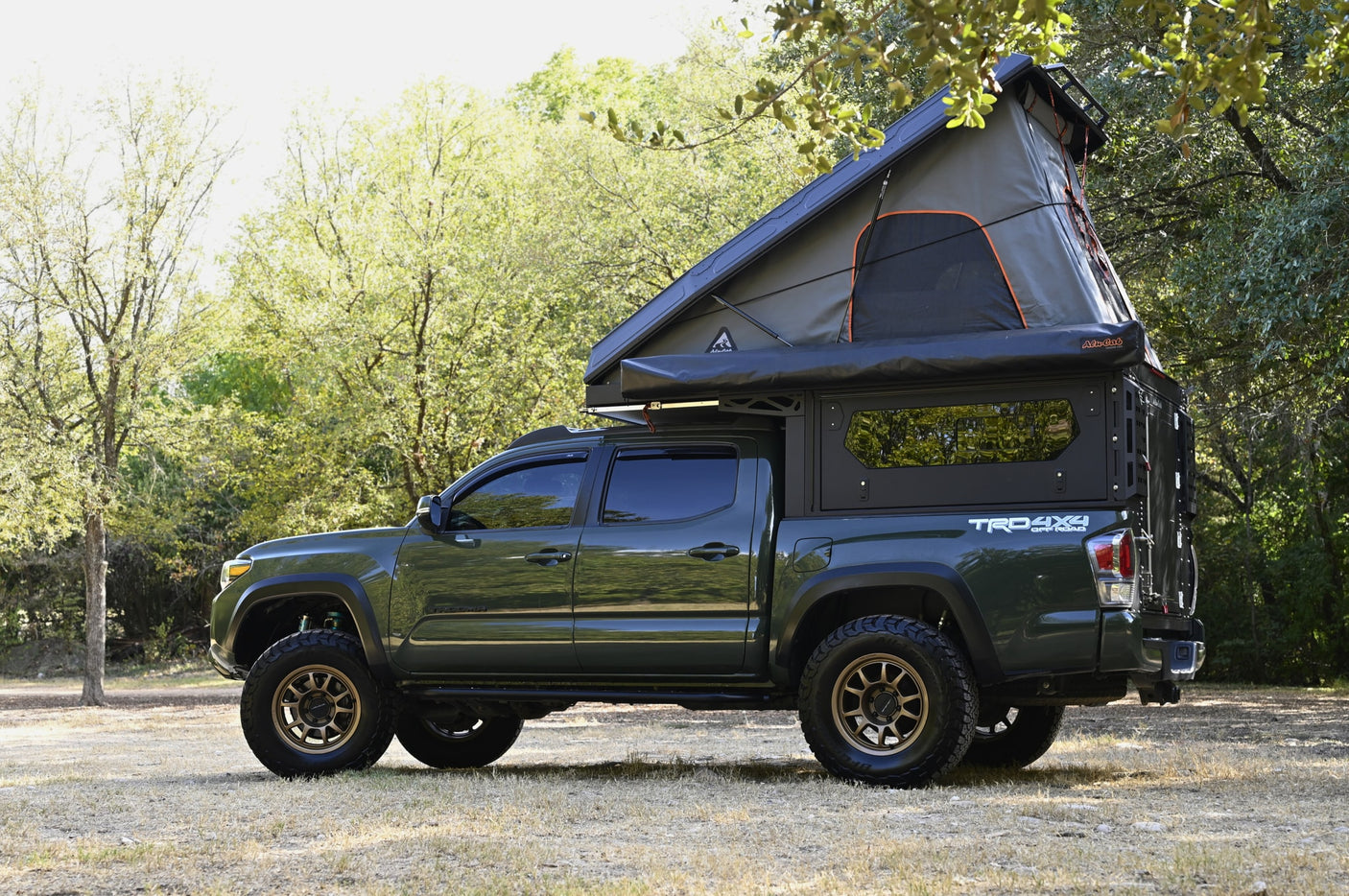 Rugged green Toyota Tacoma with an Alucab rooftop tent, perfect rv rental for off-road camping and adventure.