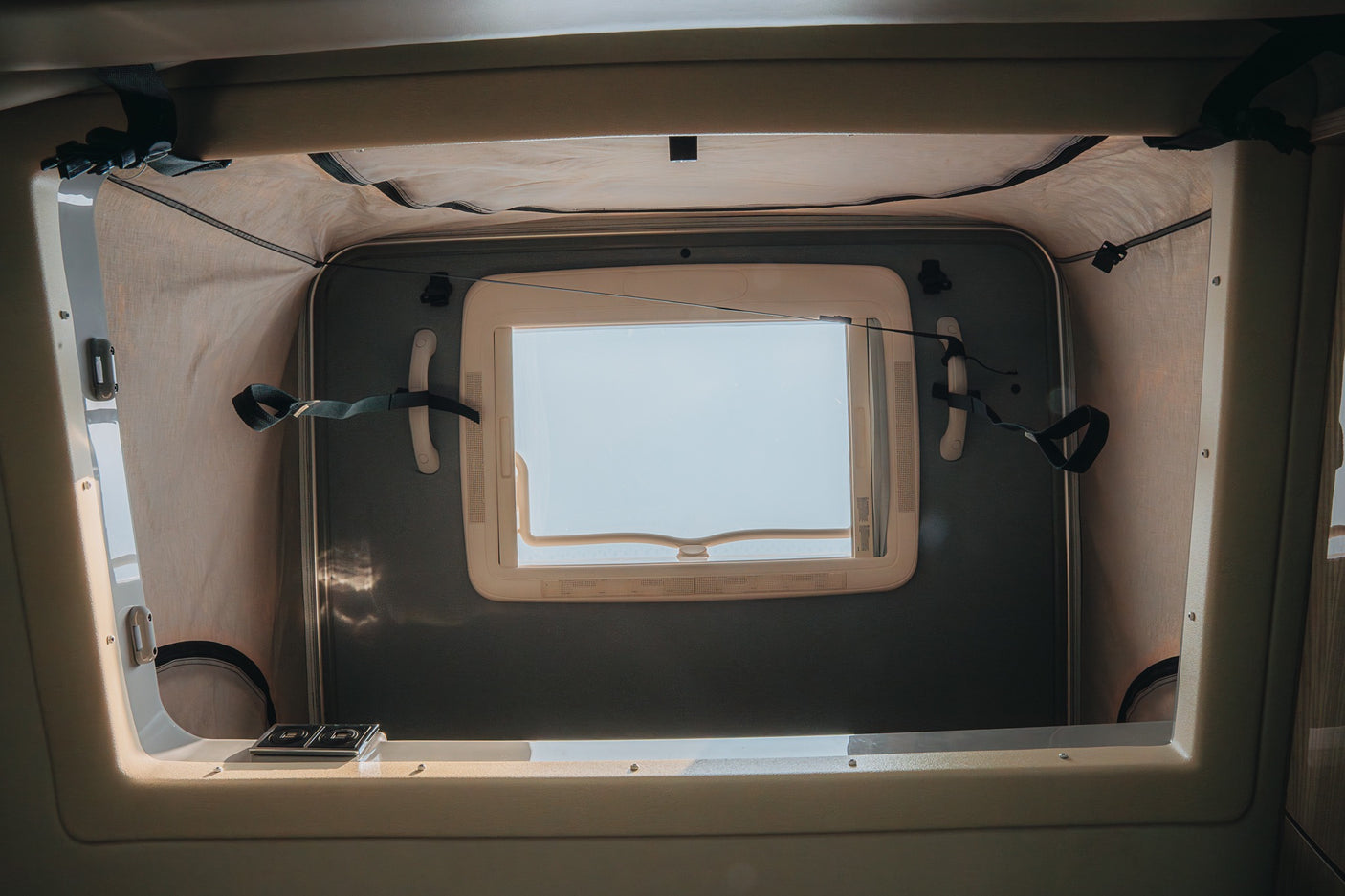 Bright camper van pop-top tent in an RV rental, showing an open window, fabric walls, and securing straps.