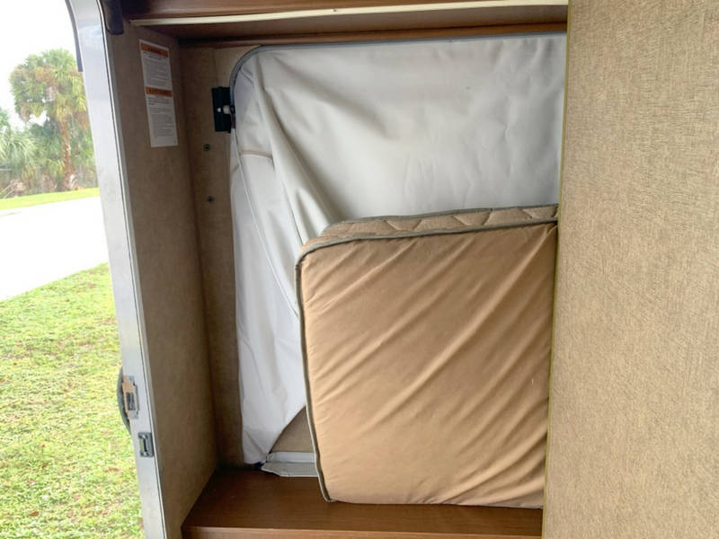 RV rental: Folded bed/mattress inside a camper's pop-out section, maximizing interior space.