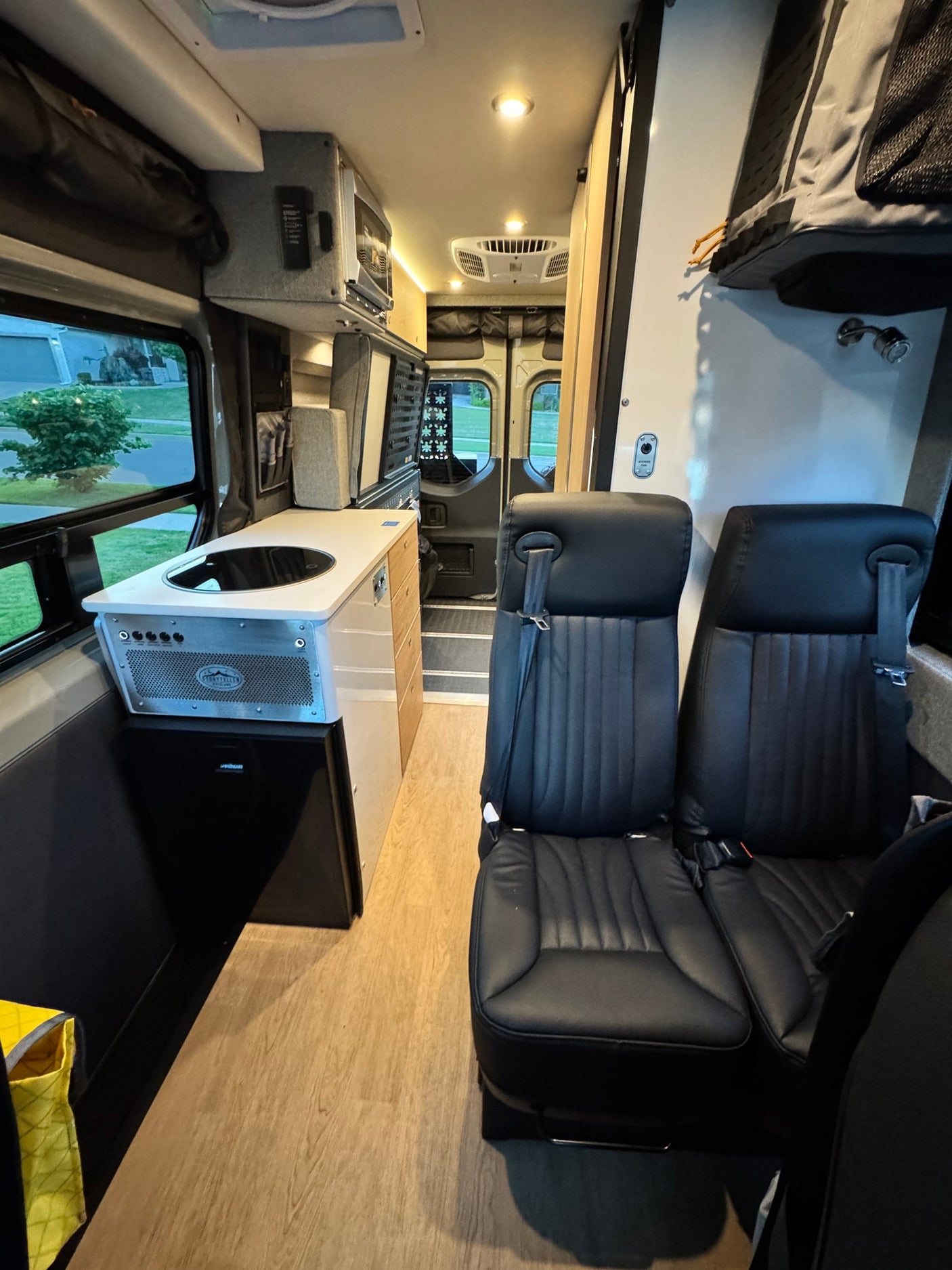 Spacious camper van RV rental interior with modern kitchen, comfortable seating, microwave, and overhead storage for adventures.