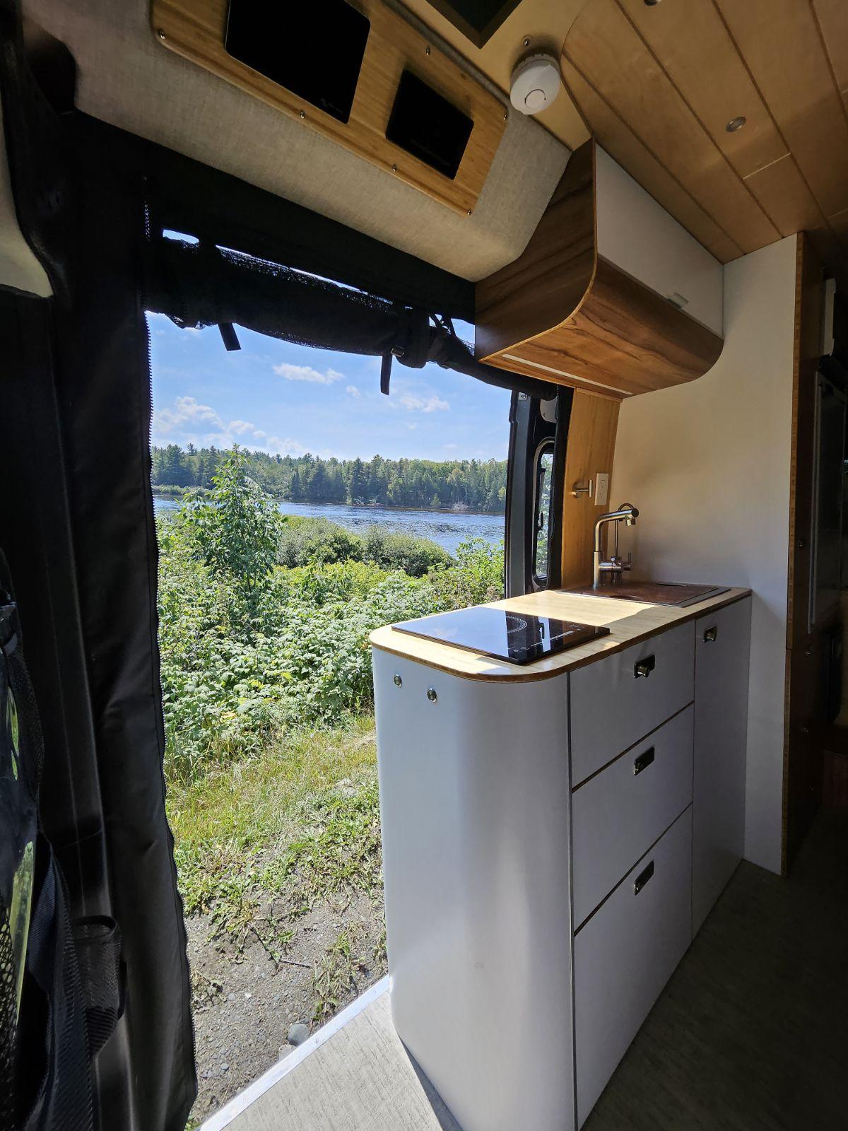 parked by trees.|Bright rv rental interior: compact kitchen