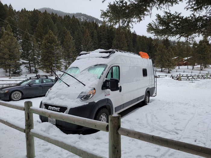Snow-covered white RV rental van, perfect for winter adventures in the mountains.