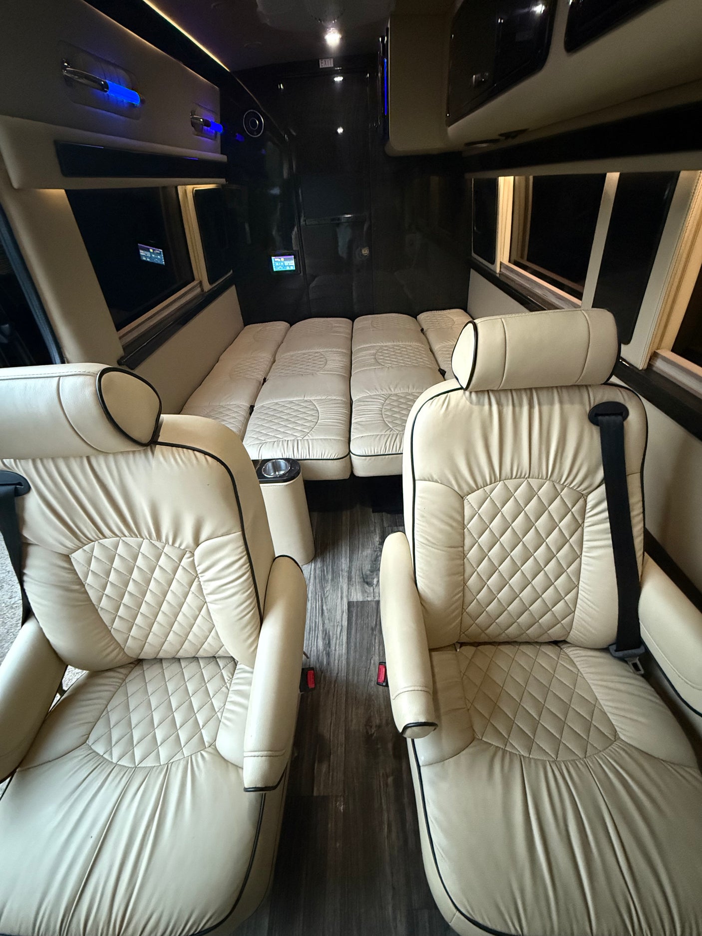 Luxurious RV rental interior featuring plush cream seats and a convertible bed, perfect for comfortable travel.