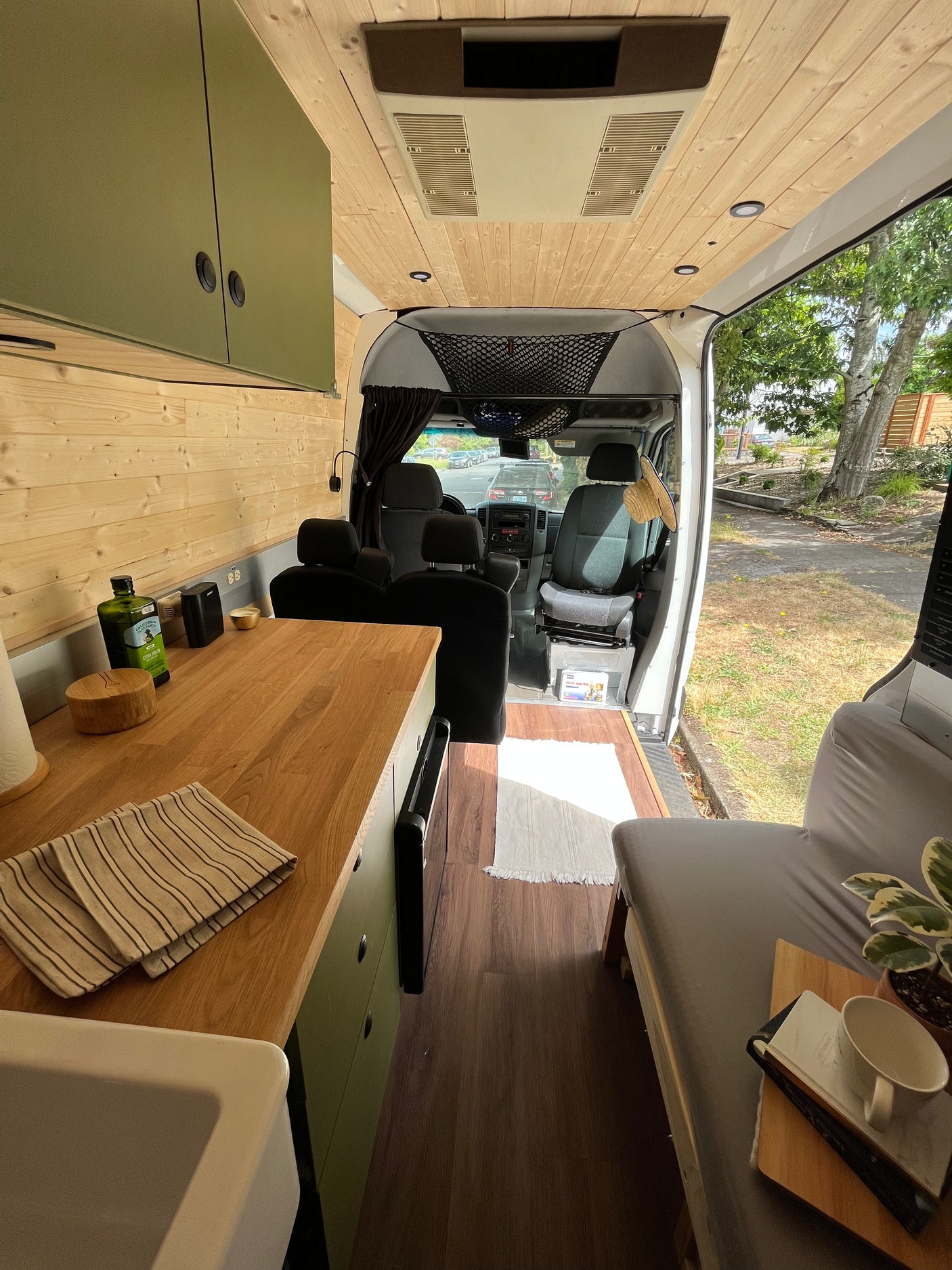 Inside a modern RV rental, showcasing a functional kitchen, cozy bed, and bright wooden interior.