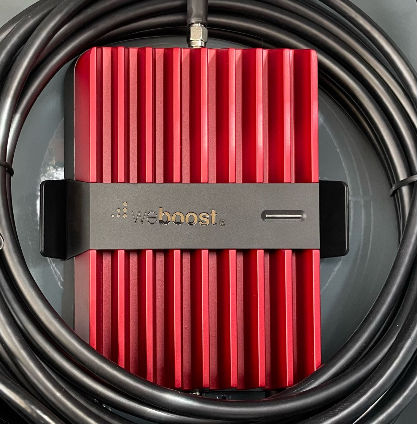 Red weBoost cellular signal booster with black cables, perfect for an RV rental to boost mobile signal.