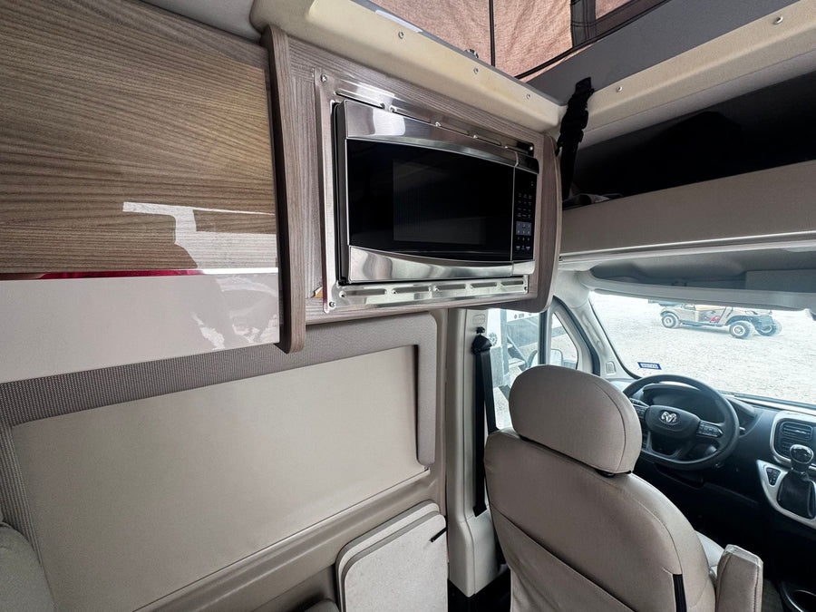 RV rental with a sleek, built-in microwave, modern wood-grain cabinetry, and comfortable driver's seat.