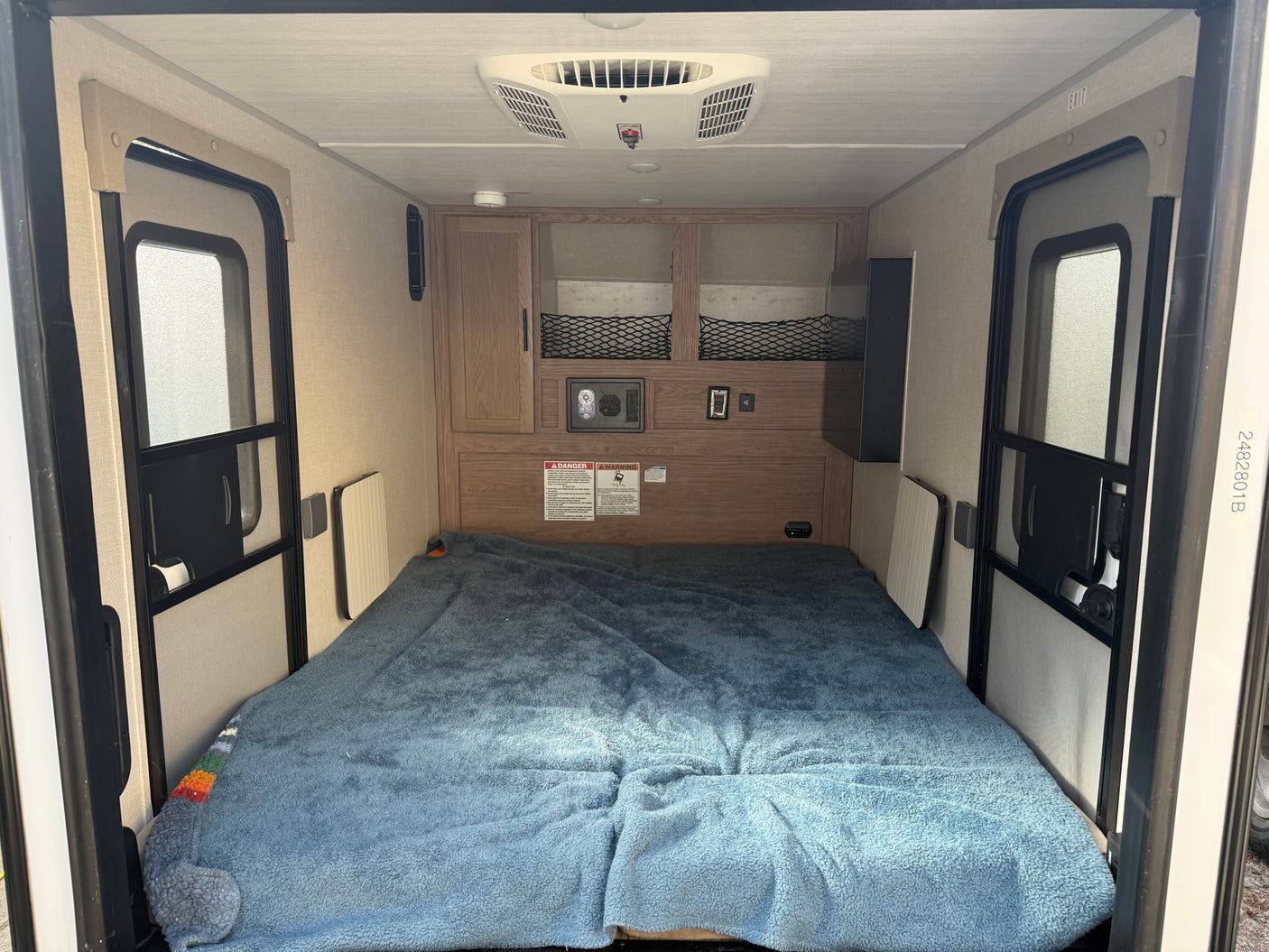 RV rental interior features a full bed, dual screen doors, overhead AC, and built-in storage for travel.