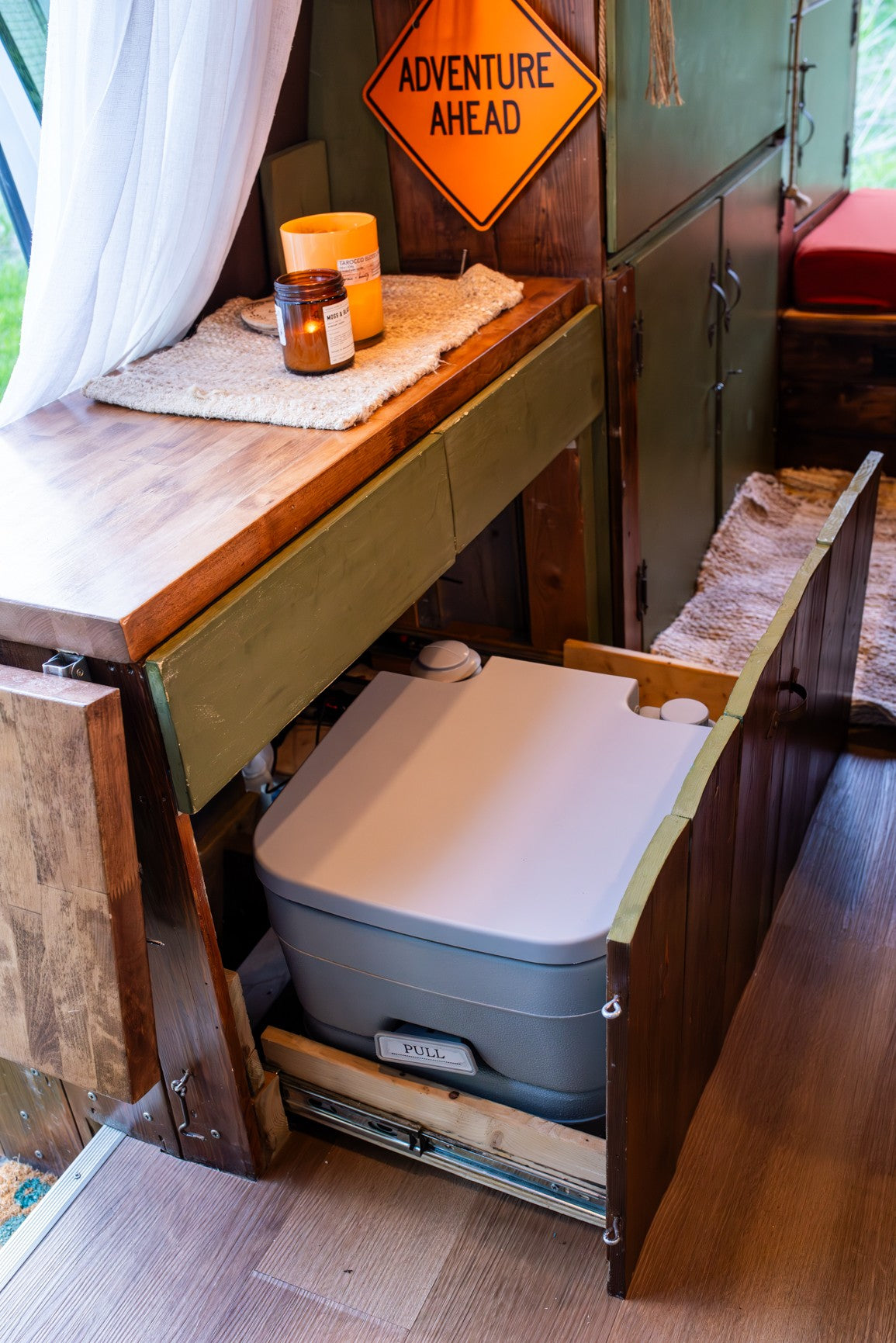 RV rental: Smart camper interior with a hidden pull-out toilet and cozy decor for adventure travel.