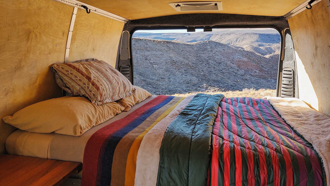 and a scenic desert window view.|This cozy RV rental interior showcases a functional camper van setup with a bed — photo 2