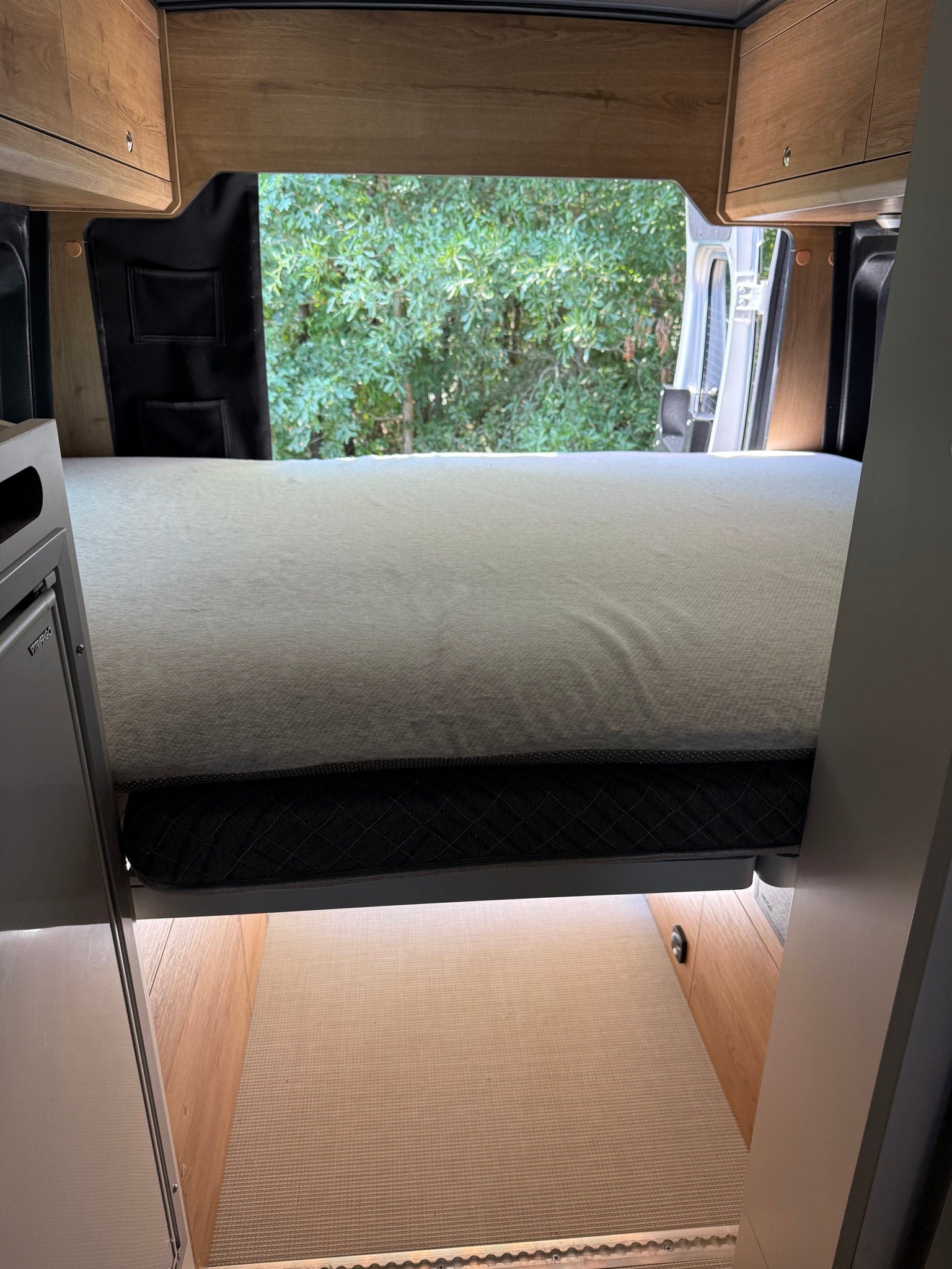 and a large window with a bug screen.|Modern RV rental interior with light gray seating
