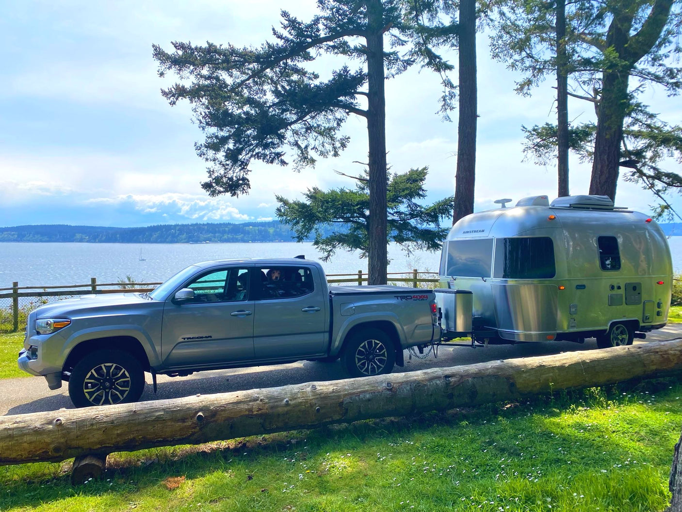 Enjoy serene waterside camping: A silver truck tows an Airstream travel trailer, perfect for an rv rental escape.