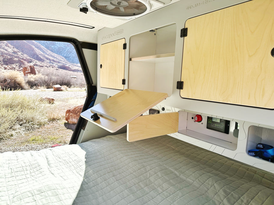 Inside an Escapod RV rental: cozy bed, fold-down desk, power monitor, and stunning mountain views for your adventure.