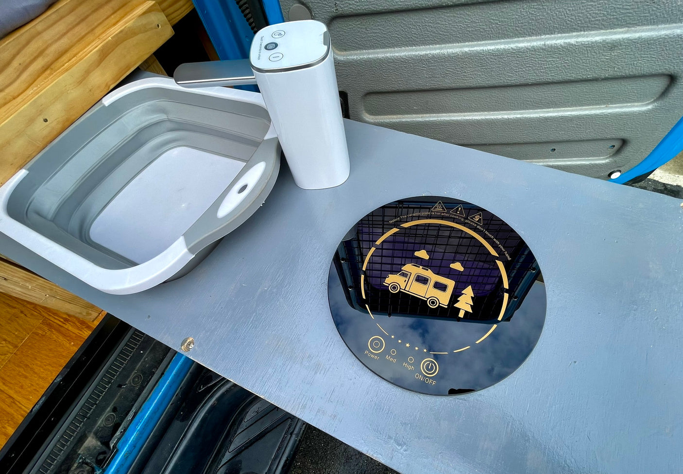 RV rental cooking setup: collapsible sink, portable water dispenser, and induction cooktop for easy camping meals.