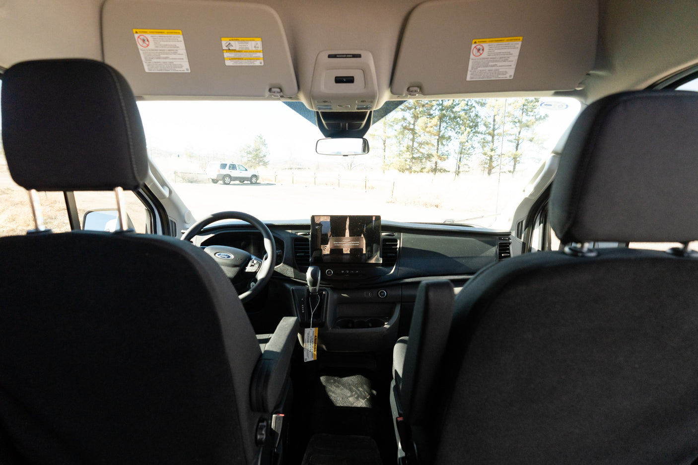 Inside a Ford RV rental van, showing the dashboard, steering wheel, and front cabin with a view of the outdoors.