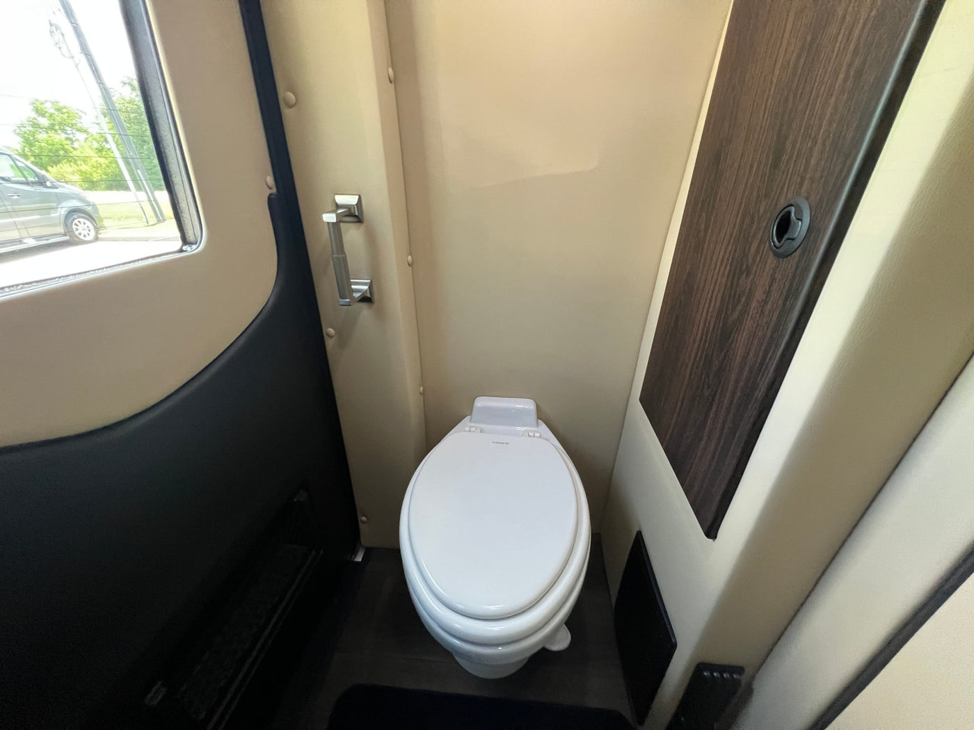 Compact bathroom in an RV rental, featuring a white Dometic toilet & window view. — photo 15