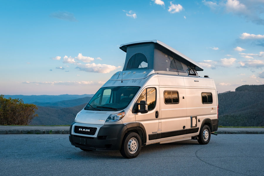 A light-colored pop-top camper van