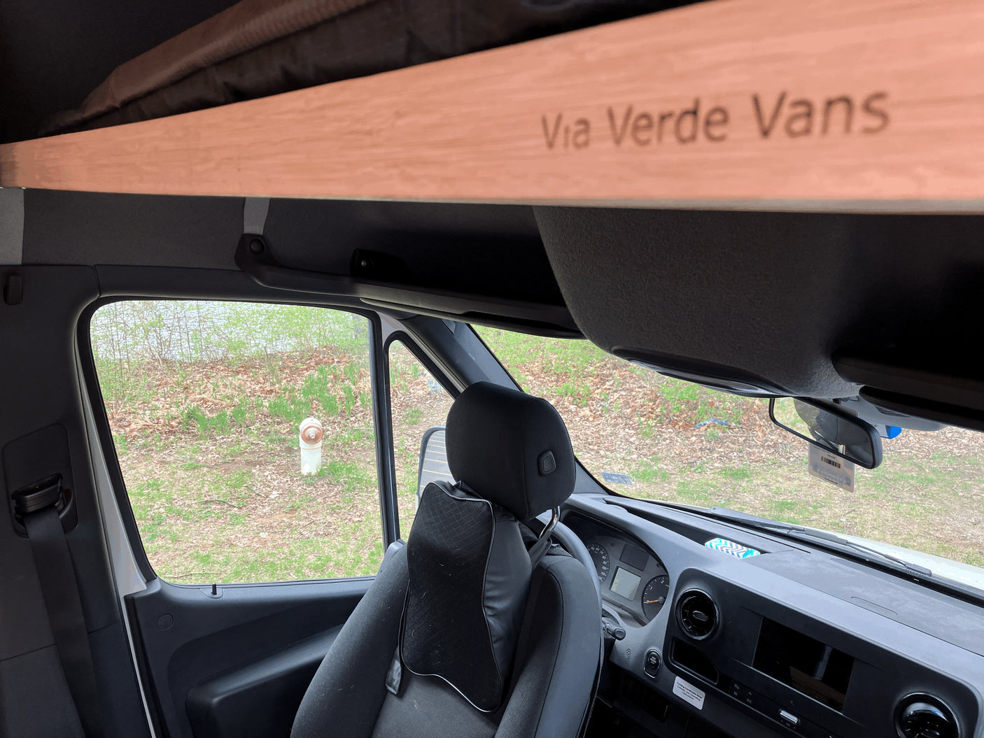 Inside an RV rental van: driver's area, dashboard, and a branded overhead beam reading "Via Verde Vans." Ideal for travel.