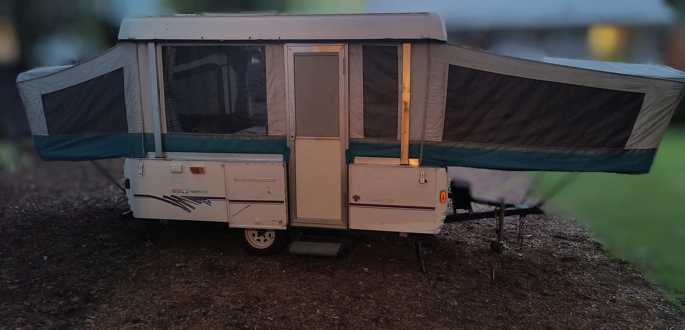 This Fleetwood Coleman pop-up RV rental is set up outdoors, ready for a camping trip. Perfect for an RV adventure.