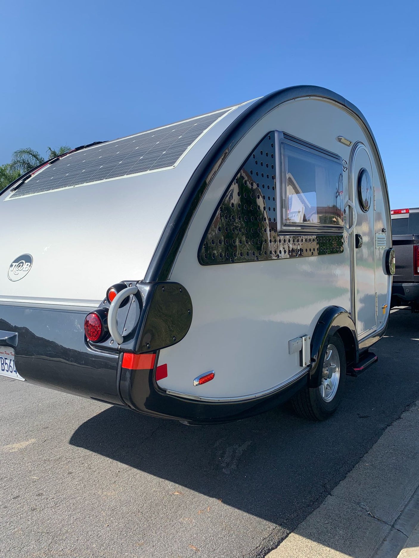 Modern teardrop travel trailer with solar panels, ideal for an RV rental adventure.