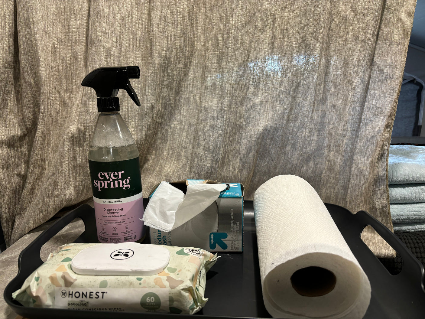 Cleaning essentials for an RV rental: disinfecting spray, wipes, paper towels, and trash bags on a tray.