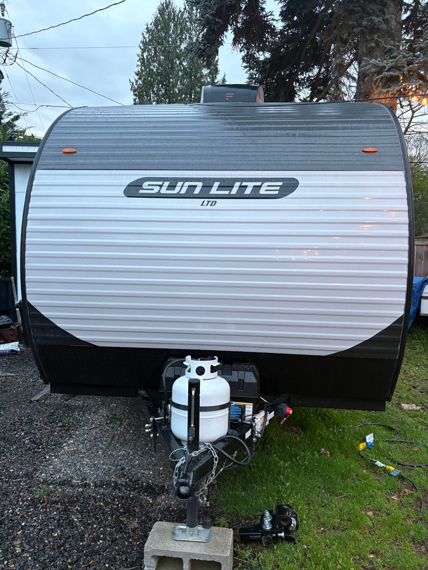 Front view of a Sun Lite Ltd travel trailer, featuring propane tank and hitch. Ideal for your next rv rental adventure!