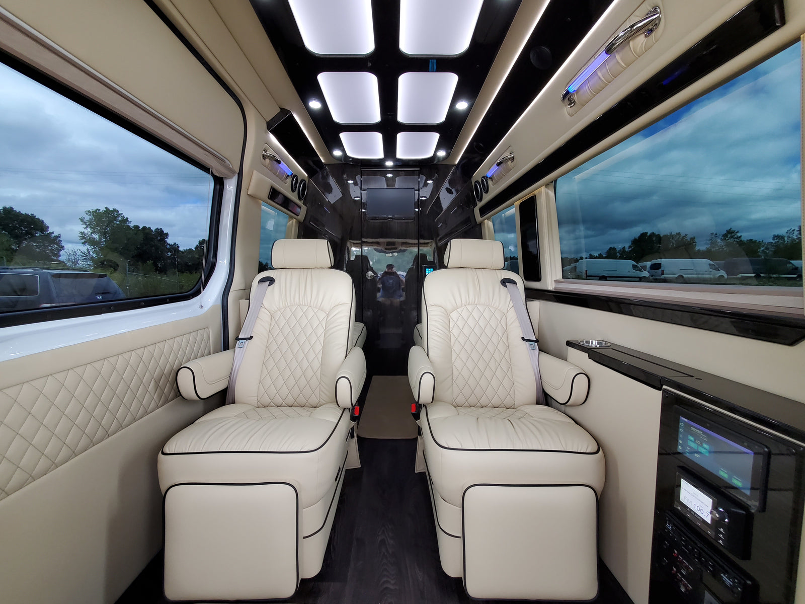 and premium ceiling lighting.|Luxurious custom RV rental interior with cream leather seats