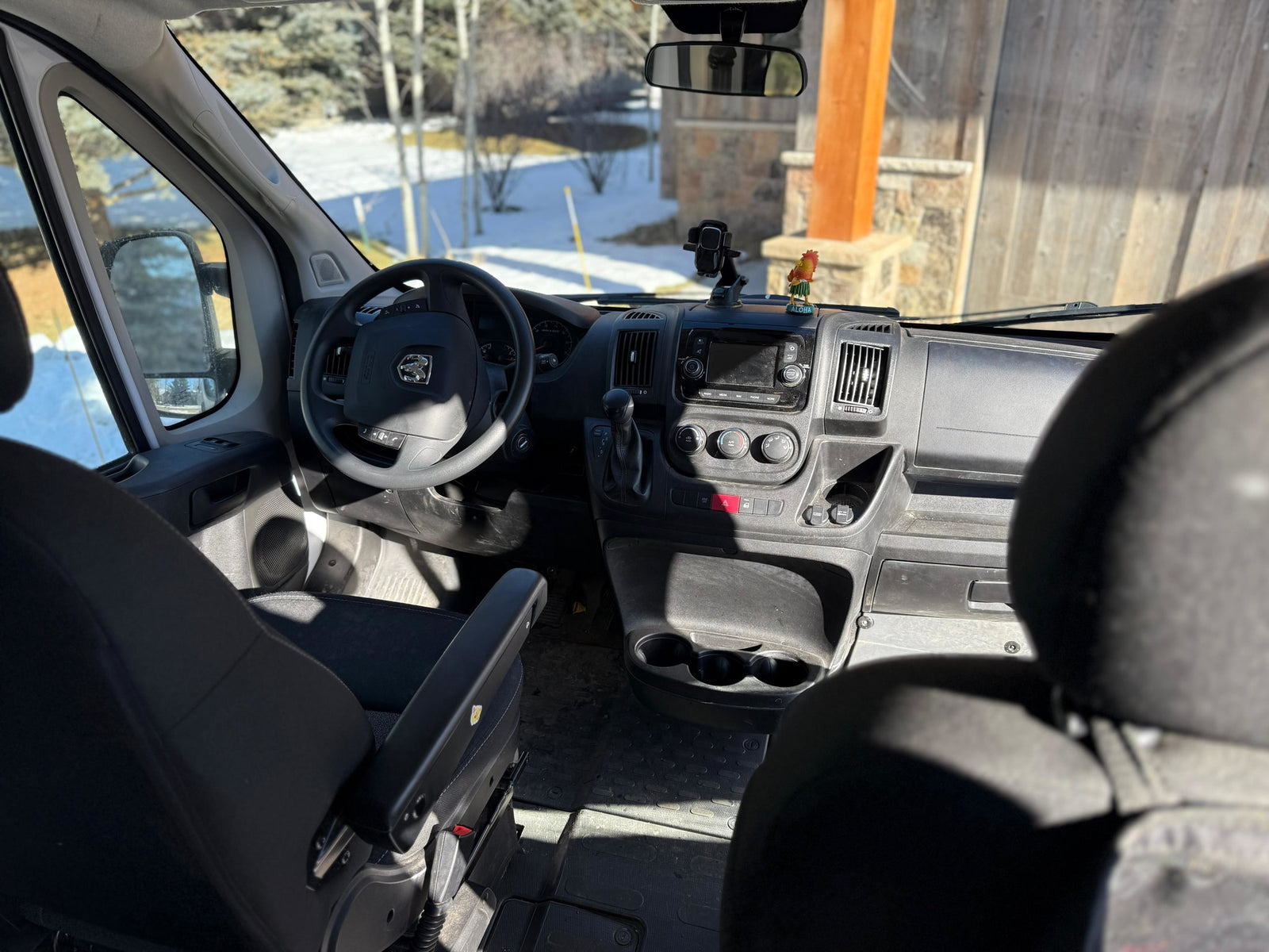 Inside an **rv rental** van. Driver's cockpit view of the dashboard, steering wheel, and snowy landscape outside.