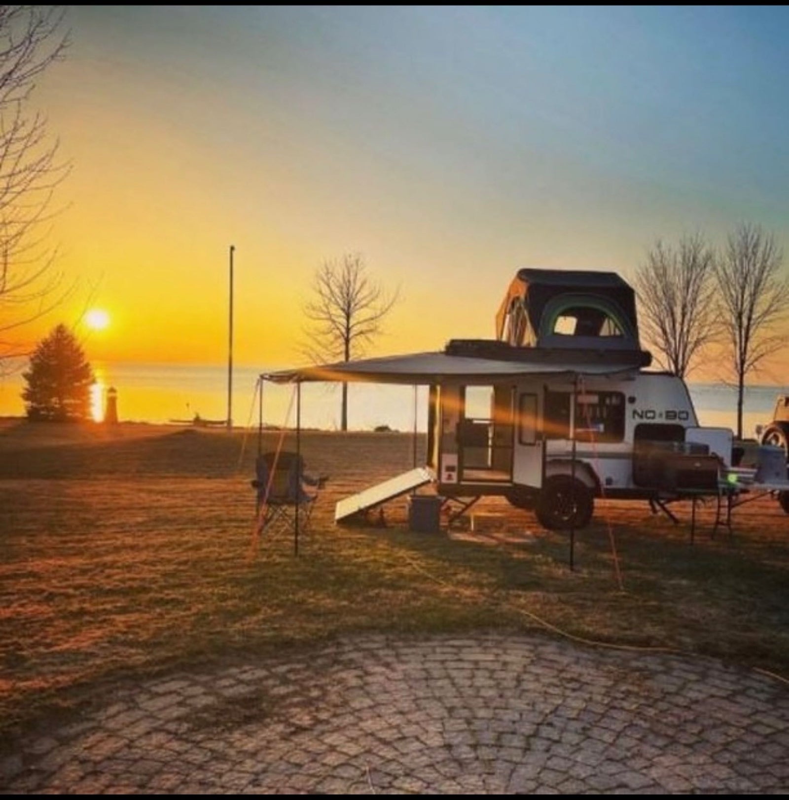 offers an ideal outdoor adventure setup amidst colorful trees.|This RV rental features a convenient pull-out outdoor kitchen with a gas stove and Truma portable refrigerator for camping meals.|RV rental: Outdoor kitchen with stove