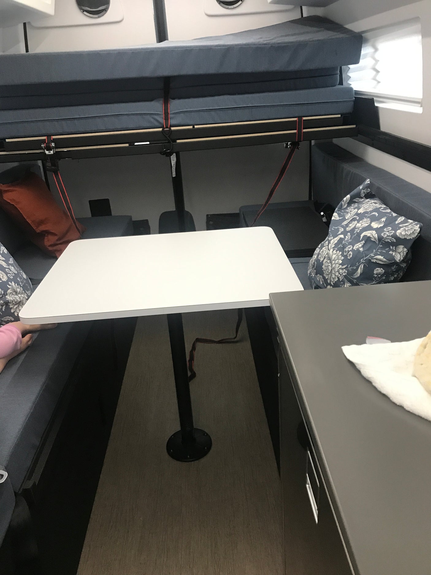 RV rental interior: a versatile space with a folded bunk bed, dining table, and plush bench seating for comfortable journeys.