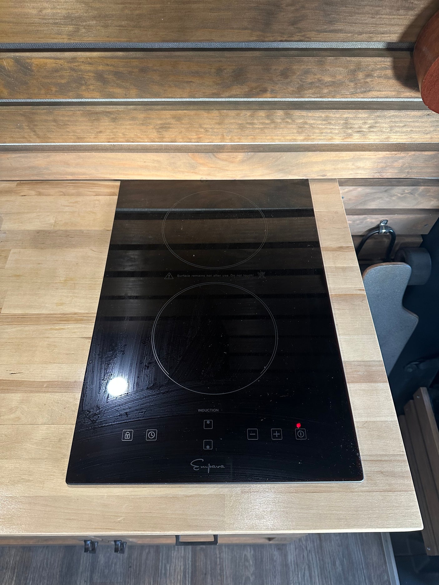 Modern Empara induction cooktop with touch controls on a wood countertop in an RV rental kitchen, ideal for road trip cooking.
