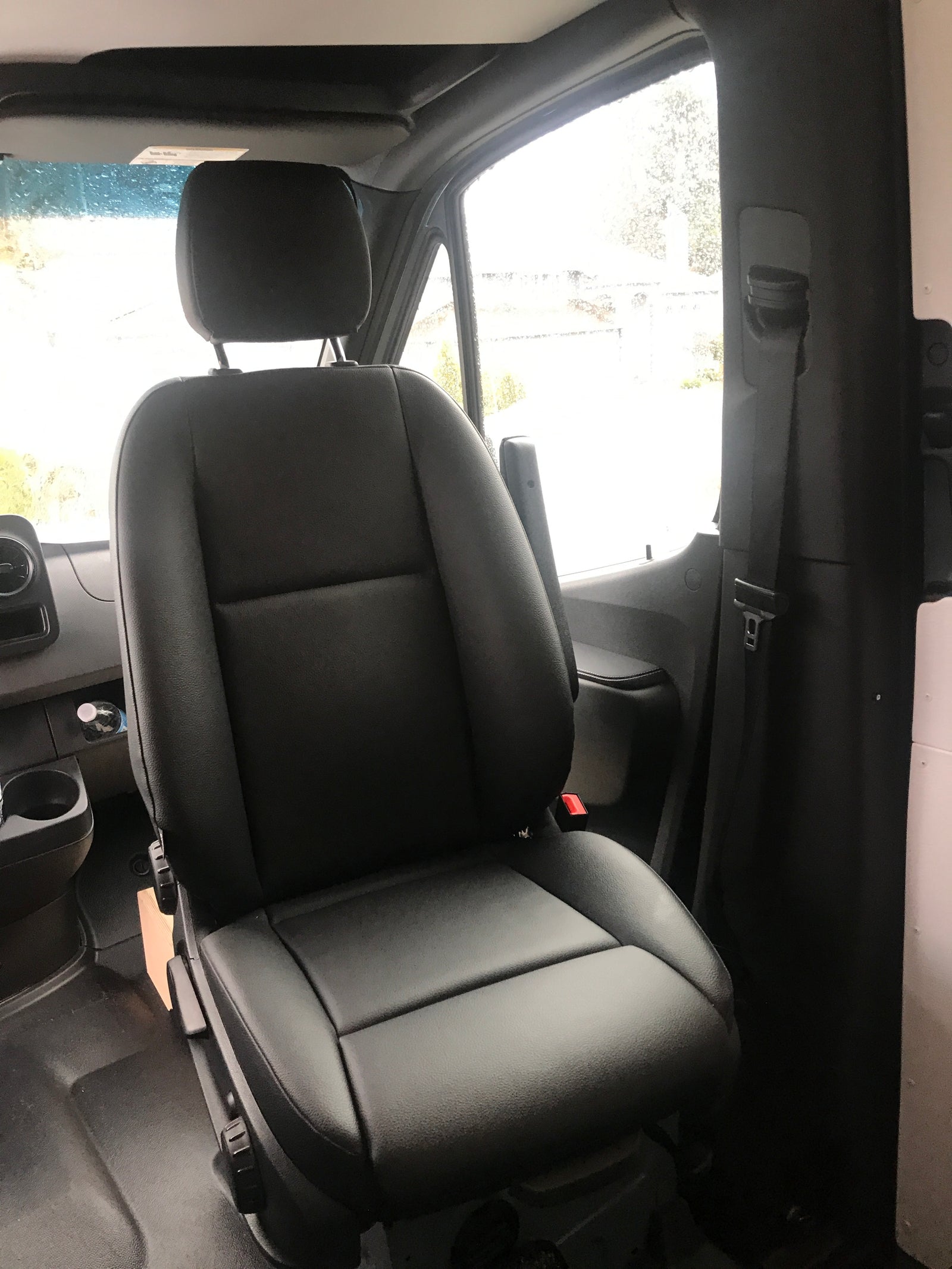View of a spacious black passenger seat inside an RV rental van, featuring an armrest and seatbelt, ready for your travels.