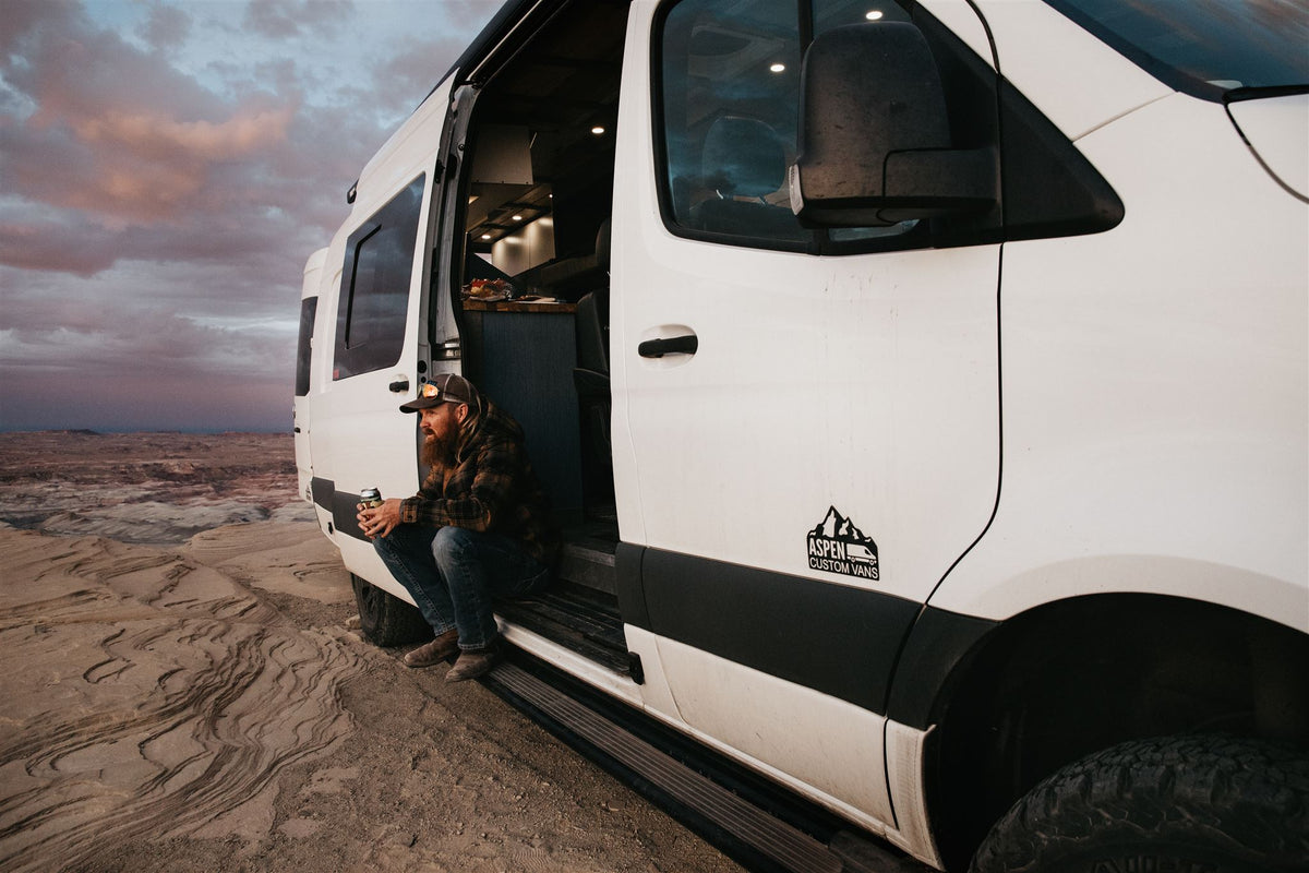 eroded landscape under a cloudy sky.|Bearded man rests by his open camper van door — photo 3