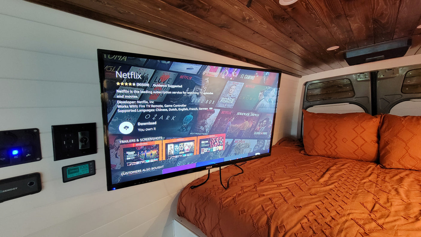 Cozy RV rental interior featuring a large TV with Netflix, a comfy bed, and a Renogy power monitoring system for entertainment.