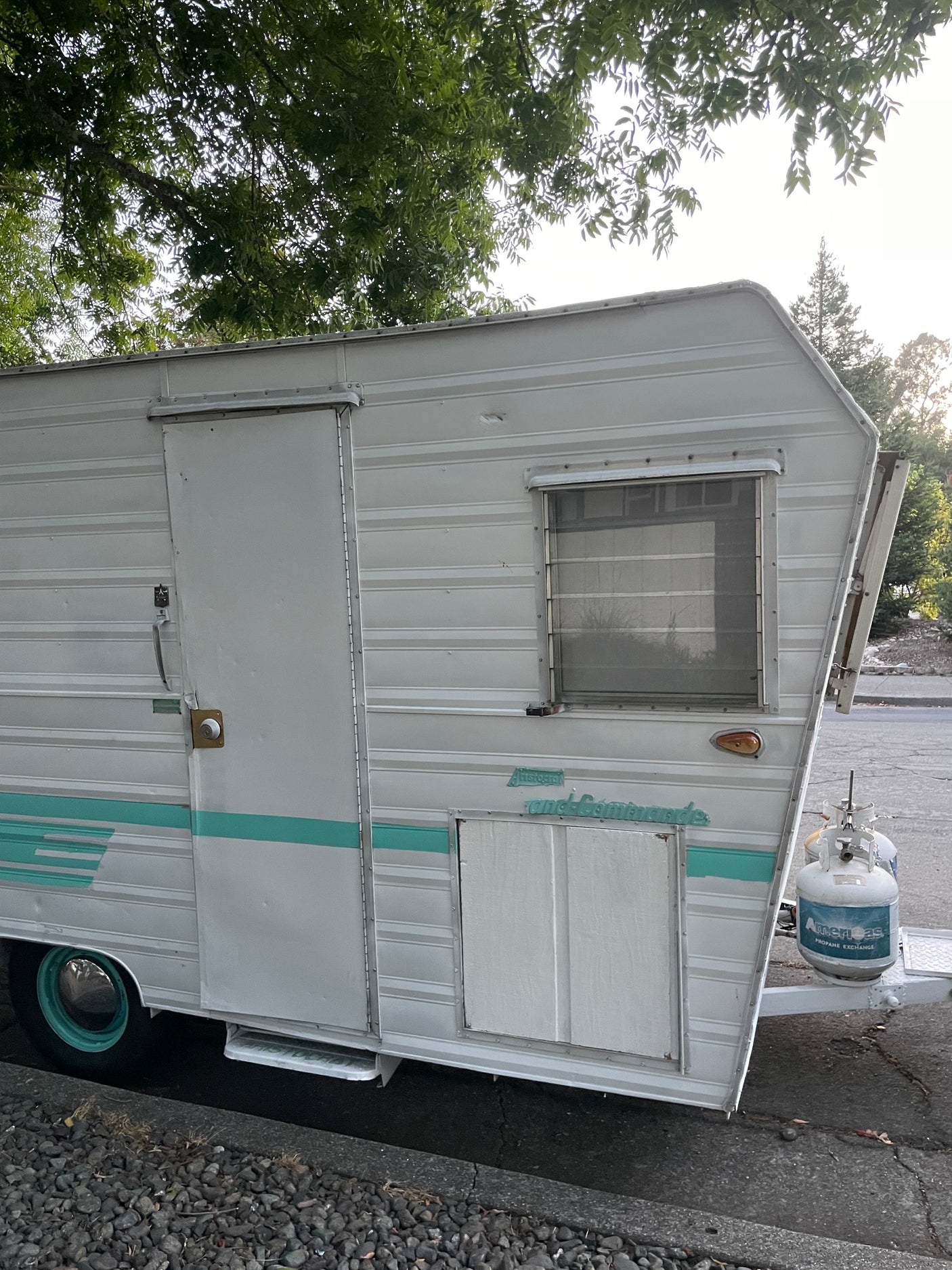 Vintage Aristocrat Land-Commando travel trailer with teal stripes, great for an RV rental adventure.
