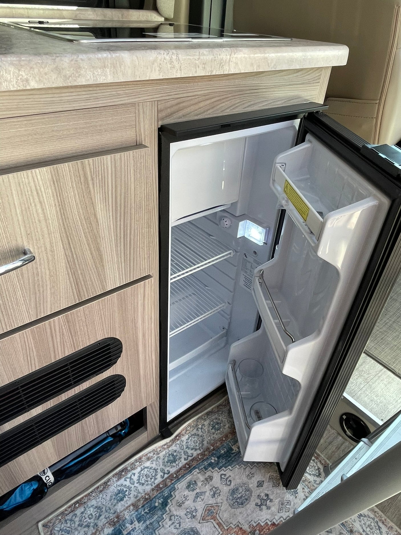 and two small camping chairs.|RV rental's compact interior: a kitchen area with microwave