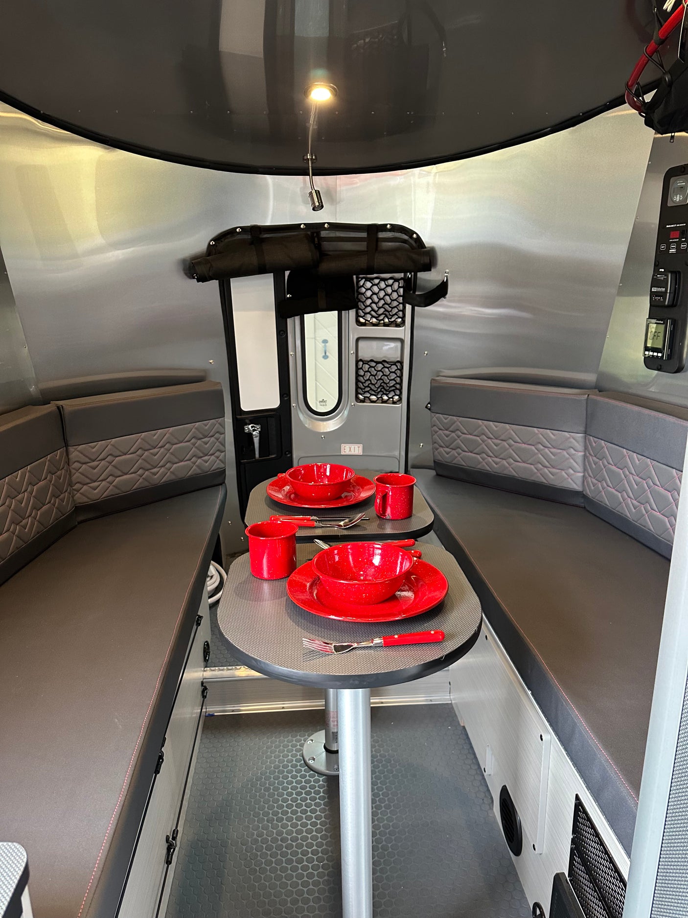Experience comfort in this rv rental interior, featuring a cozy dining area with bright red place settings & plush booth seating.