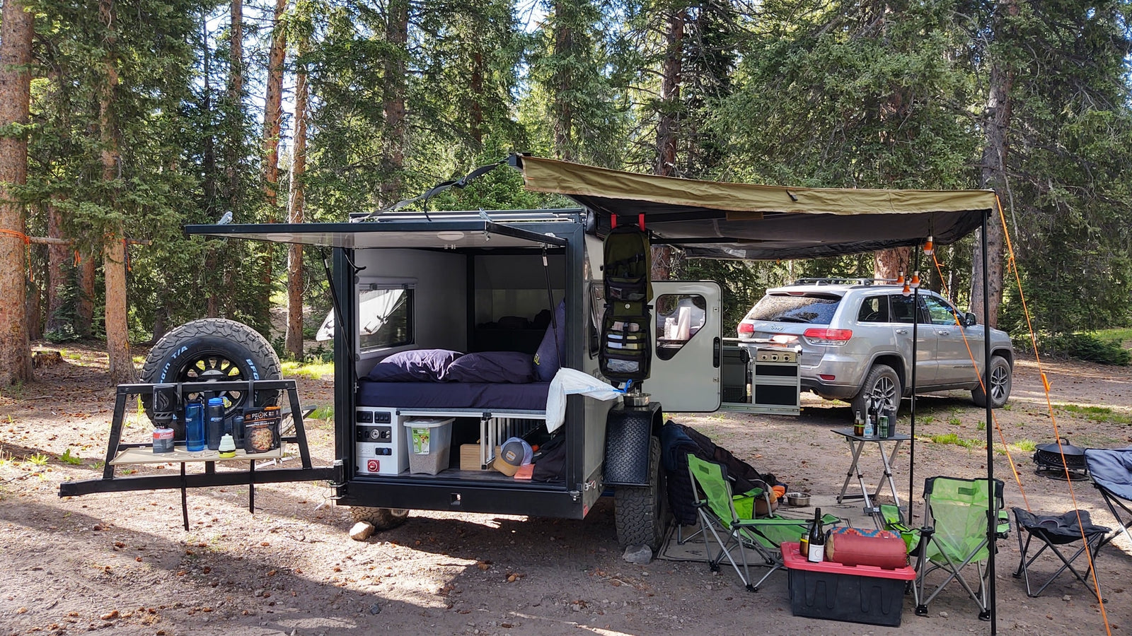 parked on a dirt road with scenic mountains & blue sky.|Off-grid RV rental adventure! This modern camper