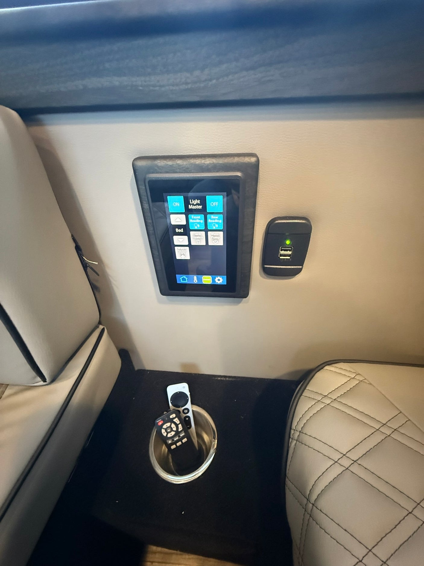 RV rental interior featuring a digital control panel, USB charging port, cup holder with remotes, and comfortable seating.