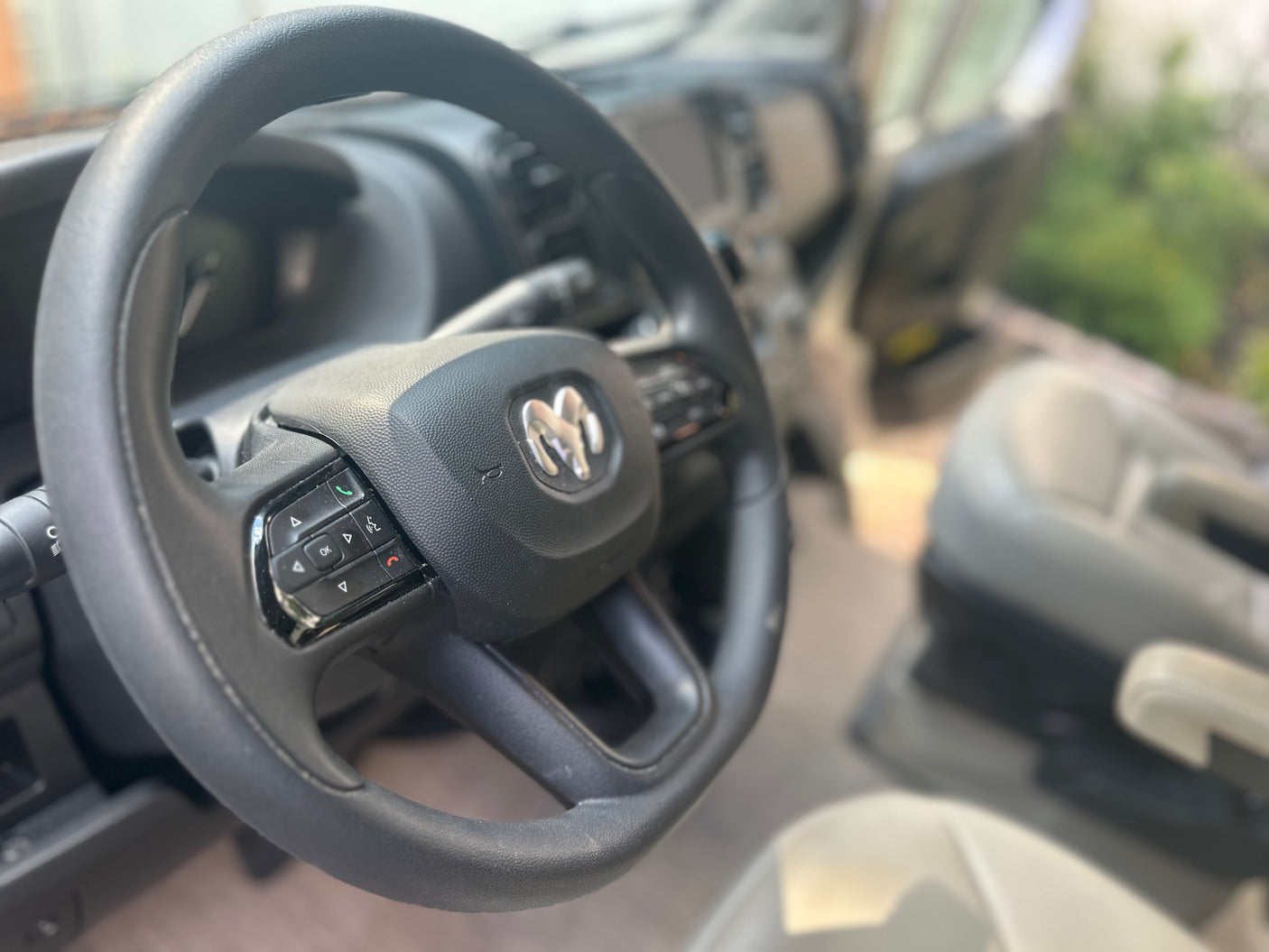 Interior of a Ram van or RV rental, focusing on the steering wheel with its distinctive logo and control buttons.