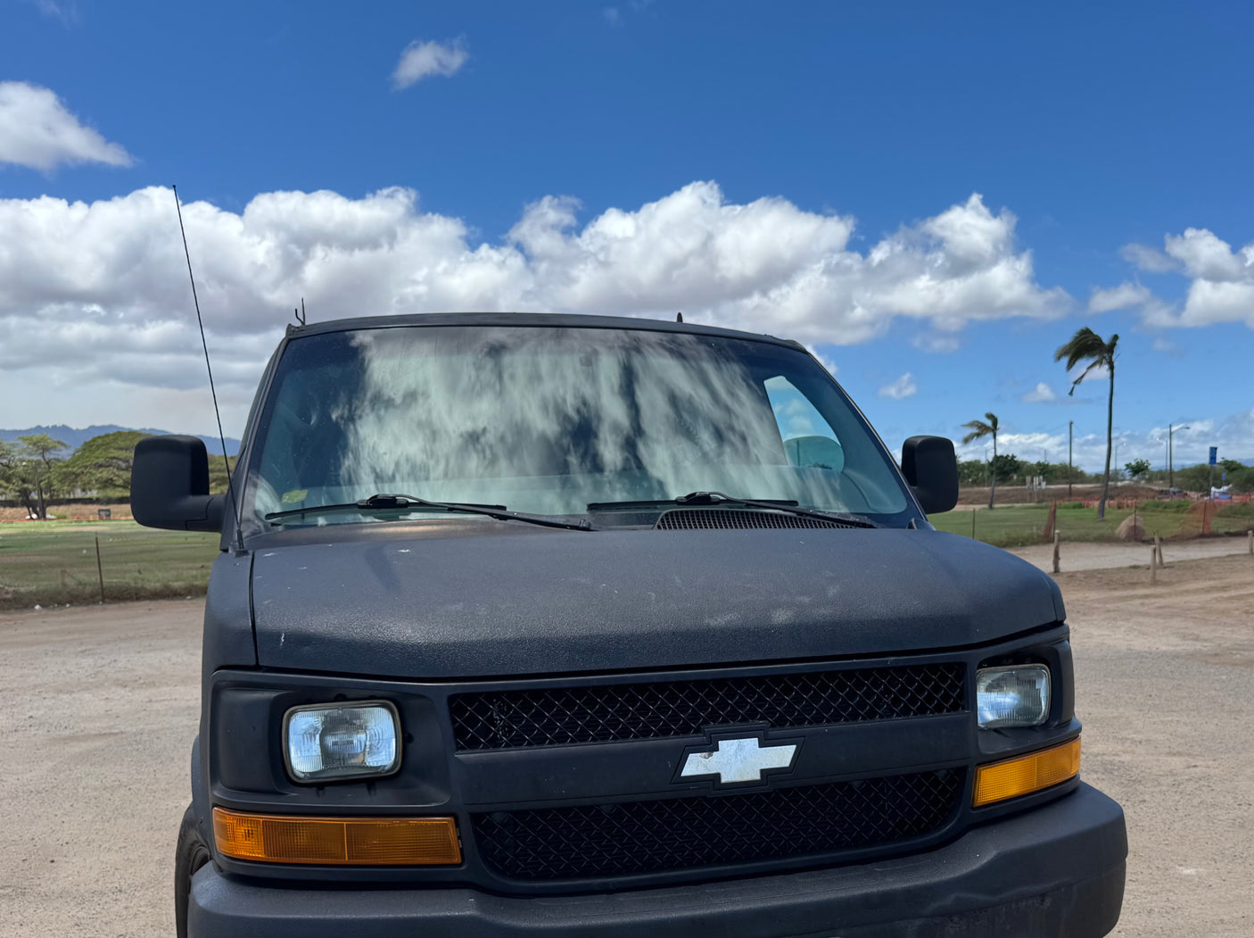 Frontal view of a rugged black Chevrolet van, suitable for rv rental or adventurous travel, under a bright sky.