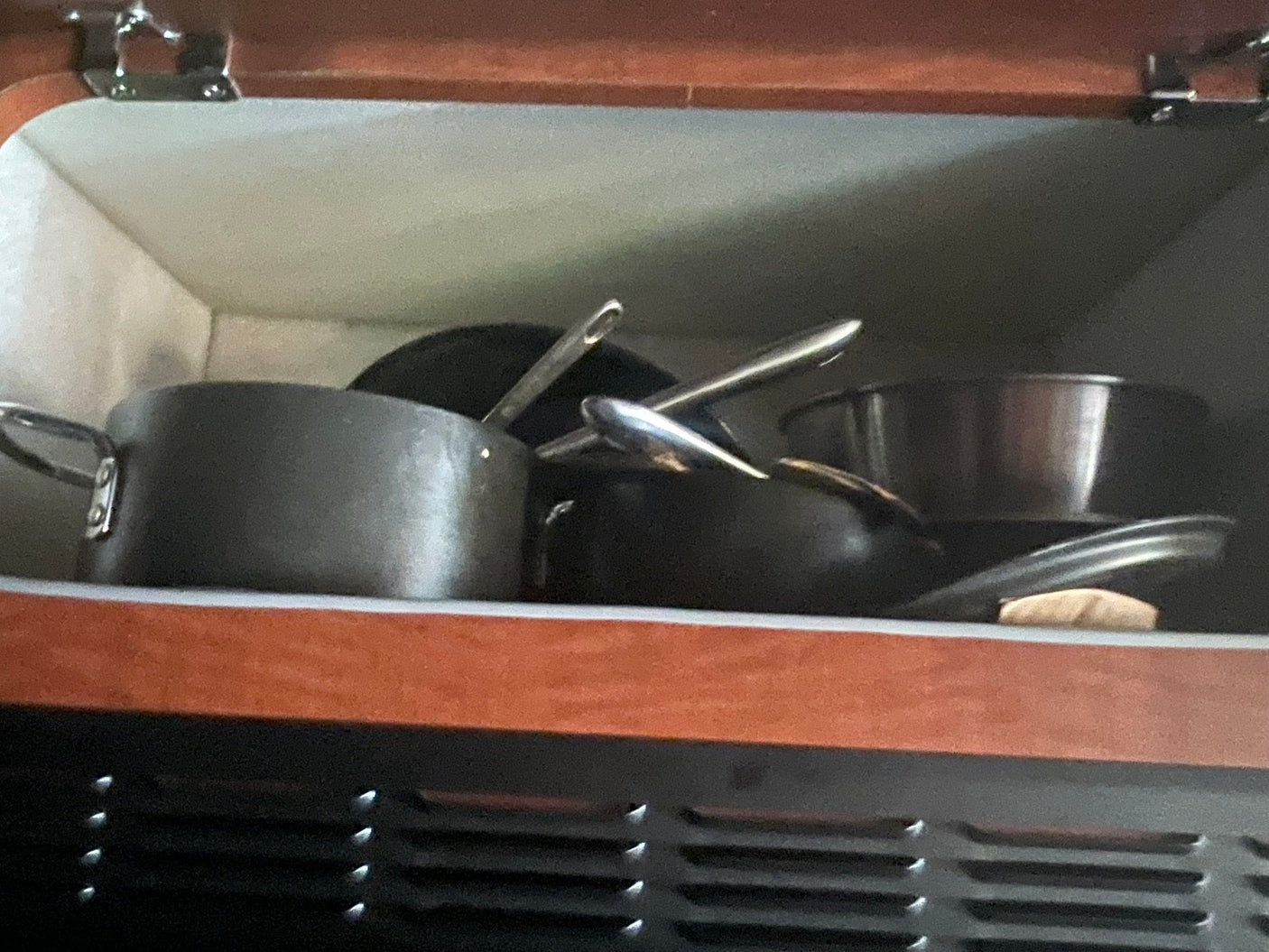 RV rental kitchen: pots and pans efficiently stored in a compact cabinet, ready for cooking adventure.